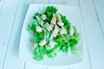 Caesar Salat mit Huhn Legen Sie Cracker auf den Salat. ?>