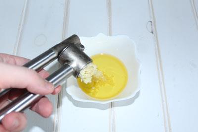 チキンのシーザーサラダ サラダドレッシングを作る。にんにくをオリーブオイルに絞ります。 ?>